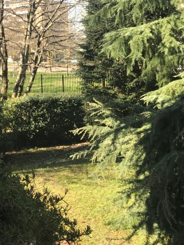 a garden with green grass and trees and a fence at B&B Borgo dei Fiori in Rozzano