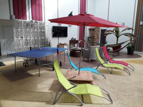a ping pong table with chairs and an umbrella at Résidence Beauvoir le Mont-Saint-Michel (9 gîtes de 2 à 5 personnes) in Beauvoir