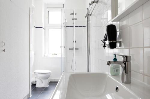 baño blanco con bañera y aseo en Apartment GREIF - Cozy Family & Business Flair welcomes you - Rockchair Apartments en Berlín