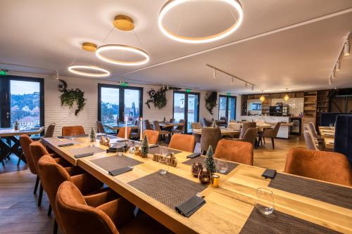 un restaurante con mesas largas, sillas y ventanas en UpperHouse Suites & More en Braşov