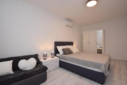 - une chambre avec un lit et un canapé dans l'établissement Seafront new apartments Zdrijac XI, à Nin