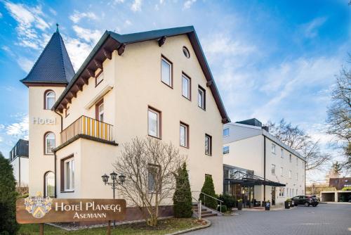 プラネックにあるHotel Asemann Planeggの時計塔のある白い大きな建物