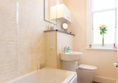 uma casa de banho com um WC, um lavatório e uma banheira em Thorne Lodge em Eastbourne