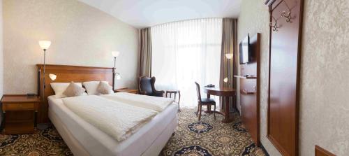 ein Hotelzimmer mit einem Bett und einem Tisch in der Unterkunft Vitalhotel König am Park in Bad Mergentheim