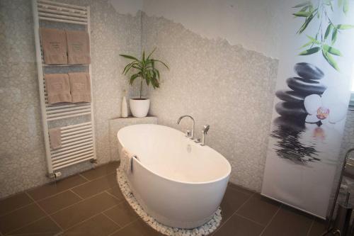 baño con bañera con una planta en la pared en Ferienwohnung Fraenkisches Paradies, en Litzendorf