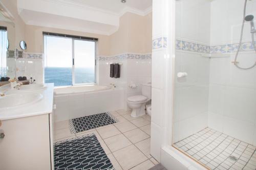 a bathroom with a shower and a sink and a toilet at Port Main Royal Ocean's Edge in St Francis Bay