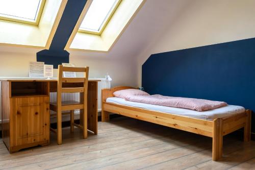 a bedroom with a bed and a desk and windows at Lima Hostel Győr in Győr