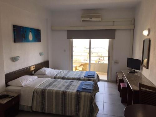 Habitación de hotel con 2 camas y escritorio en Sunflower Hotel Apartments, en Lárnaca