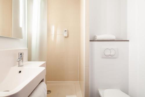 een witte badkamer met een wastafel en een douche bij B&B HOTEL Paris Saint-Denis Pleyel in Saint-Denis