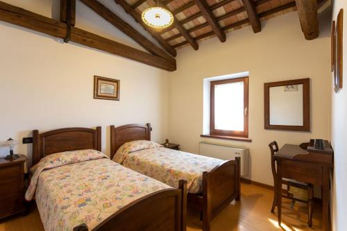 1 dormitorio con 2 camas y escritorio en Agriturismo Il Picchio, en Castiòns di Strada