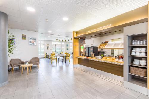 a restaurant with a counter and tables and chairs at B&B HOTEL Tours Parc Expo St-Avertin in Saint-Avertin