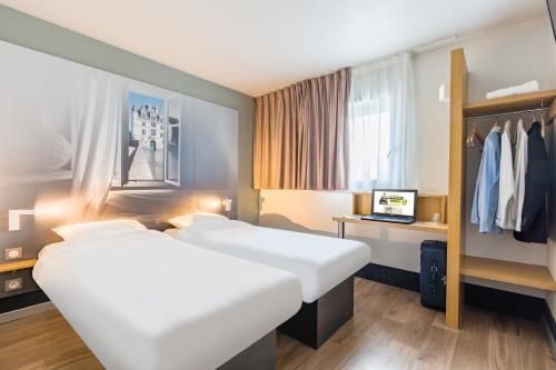 a hotel room with two beds and a wardrobe at B&B HOTEL Tours Parc Expo St-Avertin in Saint-Avertin