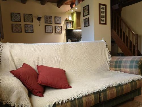 - un canapé blanc avec 2 oreillers rouges dans l'établissement Casa acogedora en Santa Leocadia, à Sainte-Léocadie