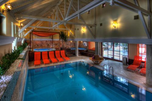 a swimming pool in a building with red chairs at Szarvaskút Hotel in Zirc