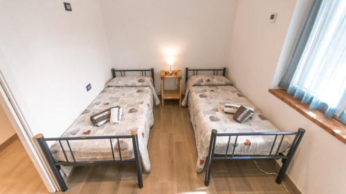 two twin beds in a room with two windows at Casa Guetti Terme di Comano in Comano Terme