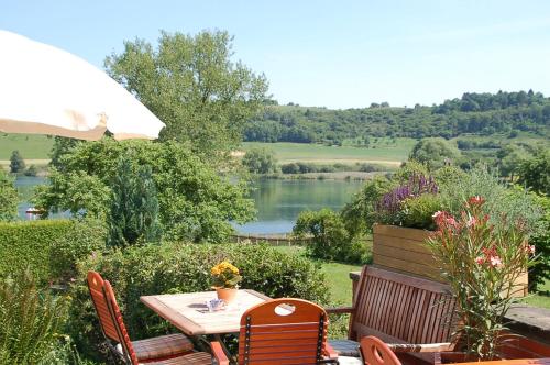 una mesa y sillas con vistas al lago en Hotel-Ferienwohnungen Cafe Maarblick, en Schalkenmehren