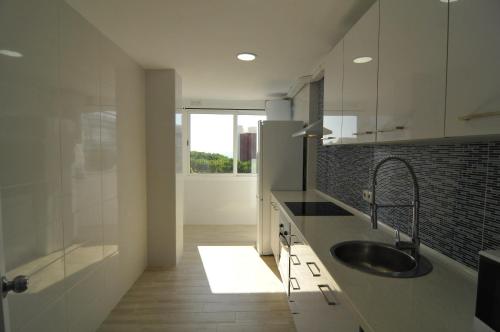 a white kitchen with a sink and a shower at HomeHolidaysRentals Solmar in Santa Susanna