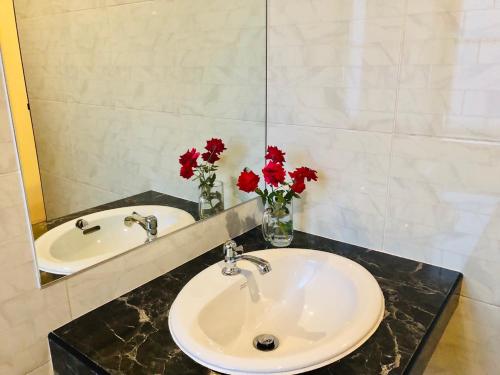 ein Badezimmer mit zwei Waschbecken und roten Blumen im Spiegel in der Unterkunft Bannsuan Amaleena in Ko Yao Noi