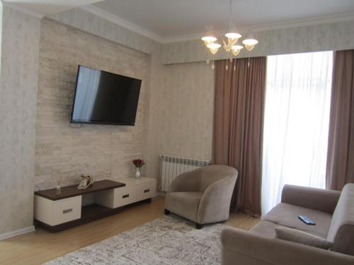 salon z kanapą i telewizorem na ścianie w obiekcie Jasmine w mieście Tbilisi City