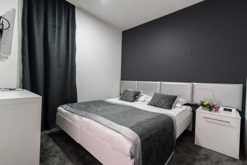 a bedroom with a large white bed with black walls at Hotel Cool Zagreb Airport in Velika Gorica