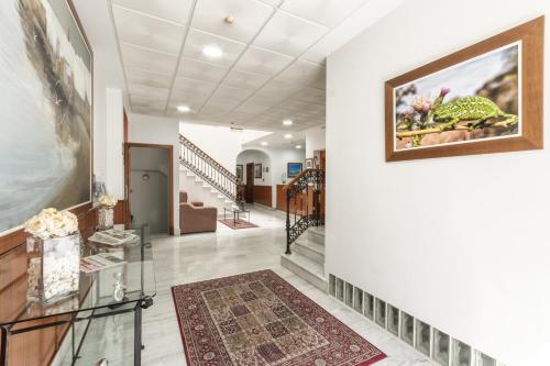 un couloir avec des murs blancs et une peinture murale dans l'établissement Hotel La Parrita, à Rota