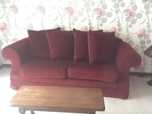 a red couch in a living room with a coffee table at Le rocher de bonnevie in Murat