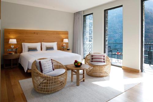 リシケーシュにあるTaj Rishikesh Resort & Spa Uttarakhandのベッドルーム1室(ベッド1台、椅子2脚、テーブル付)