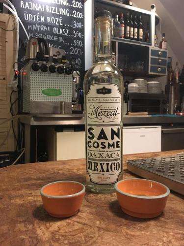 a bottle of gin sitting on a table next to two bowls at Lima Hostel Győr in Győr