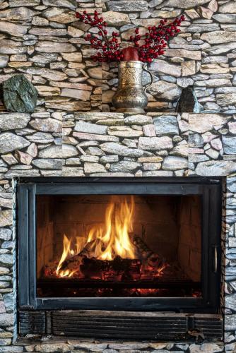 a fireplace with a stone wall with a fire in it at Matzato in Monodendri