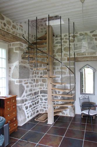 a spiral staircase in a room with a stone wall at Les Vergnes in Saint-Pardoux-le-Neuf