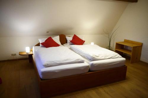 Schlafzimmer mit einem Bett mit roten und weißen Kissen in der Unterkunft Ferienhaus Herzogenreuth in Heiligenstadt
