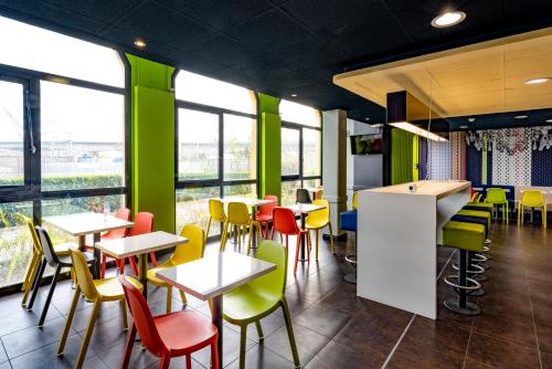 um restaurante com cadeiras coloridas, mesas e janelas em ibis Budget Vitry Sur Seine A86 em Vitry-sur-Seine