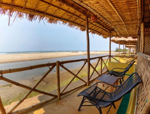 a porch with two chairs and a beach at Beach Street Eco Resort - Mandrem in Mandrem