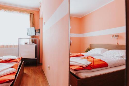 a bedroom with two beds with orange walls at Pension Rose-Trandafirul in Borsec