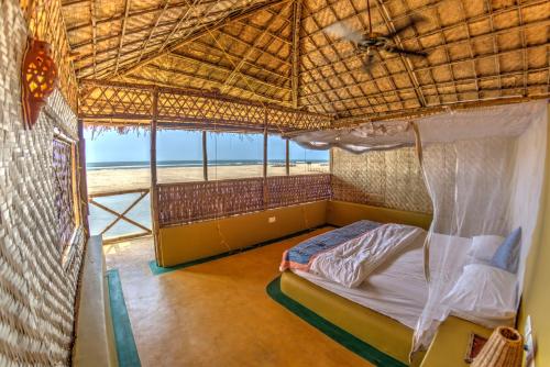 a bed in a room with a view of the beach at Beach Street Eco Resort - Mandrem in Mandrem
