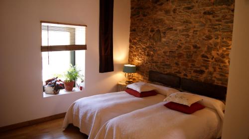 a bedroom with a bed and a brick wall at Hotel Rural Las Campares in Callejo de Ordás