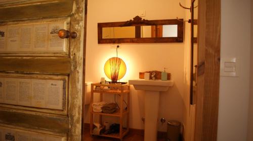 a bathroom with a sink and a lamp next to a door at Hotel Rural Las Campares in Callejo de Ordás