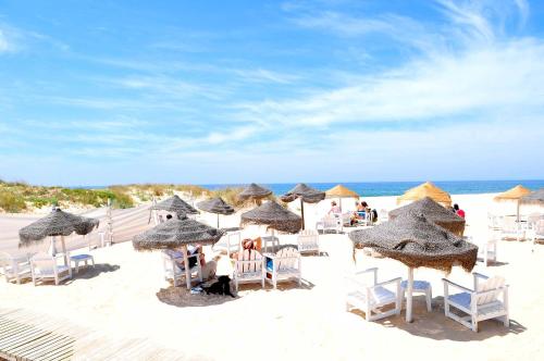 a beach with chairs and umbrellas on the beach at Lisbon Beach Apartments 1 in Costa da Caparica