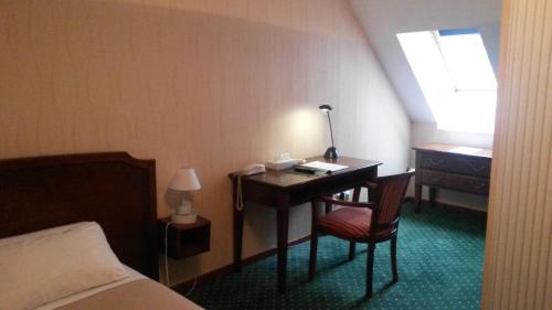 a hotel room with a desk and a bed and a window at Hôtel de La Cloche in Dole