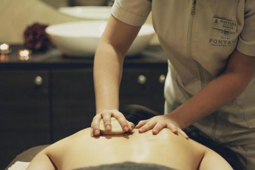 a woman getting a back massage on a persons body at Hotel Fontana Vrnjačka Banja in Vrnjačka Banja
