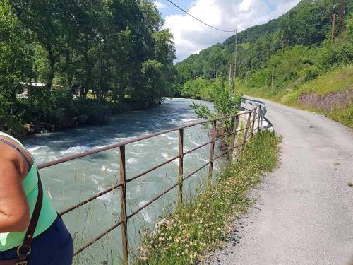 a person standing on a fence next to a river at MSK65 Pyrenees Accommodation Sarrancolin in Sarrancolin