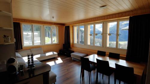 a living room with a table and chairs and windows at Ufem Egg Ferienwohnungen in Innertkirchen