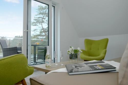 a room with two green chairs and a table with a book at Düne 74 in Ostseebad Karlshagen