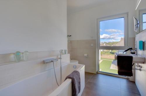 a bathroom with a tub and a sink and a window at Düne 74 in Ostseebad Karlshagen