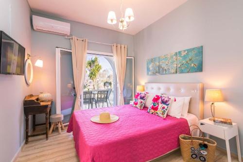 Dormitorio rosa con cama rosa y mesa en Lamda Apartments by Estia en Roda