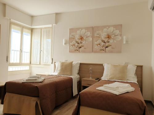 a bedroom with two beds and two paintings on the wall at Cabà Holiday Bardolino Santa Cristina in Bardolino
