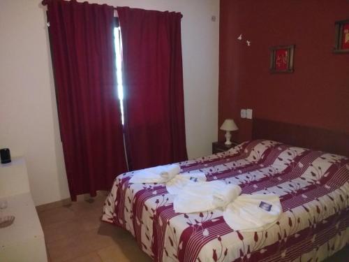 a bedroom with a large bed with red curtains at Cabañas Quinco in Merlo