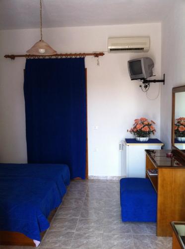a room with a blue bed and a tv at Porto Milos in Adamantas
