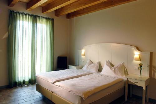 Un dormitorio con una gran cama blanca y una ventana en Agriturismo Le Vai, en Bardolino