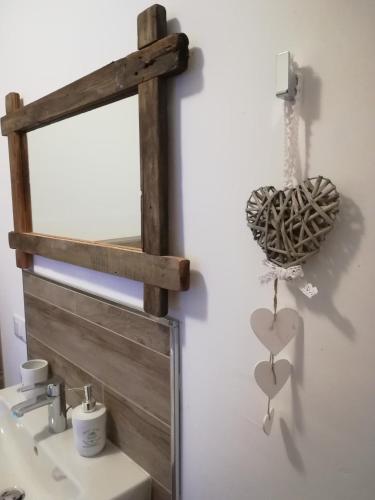 a mirror over a sink with a heart ornament on a wall at DOLCE DORMIRE in Rovereto